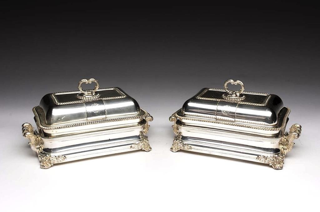 PAIR OF SHEFFIELD PLATE COVERED ENTREE DISHES: On fitted warming stands with foliate capped feet and handles, applied later crest to lid, circa 1820. W 36 cm (14 1/8 in.)