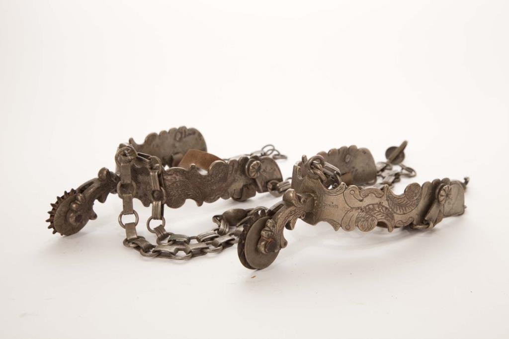 PAIR OF SPANISH COLONIAL SILVER PLATED SPURS: With engraved decoration and small wheels, 19th century. L 17.8 cm (7 in.)