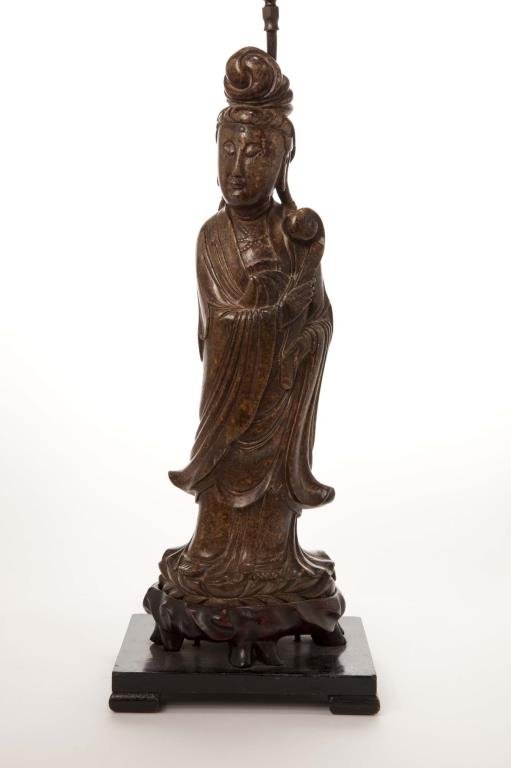 CHINESE SOAPSTONE CARVING OF GUANYIN: Finely carved on a lotus base and holding a ruyi, incised details to her robe, on carved fitted stand; 19th century. 43.5cm (17 1/4 in.)