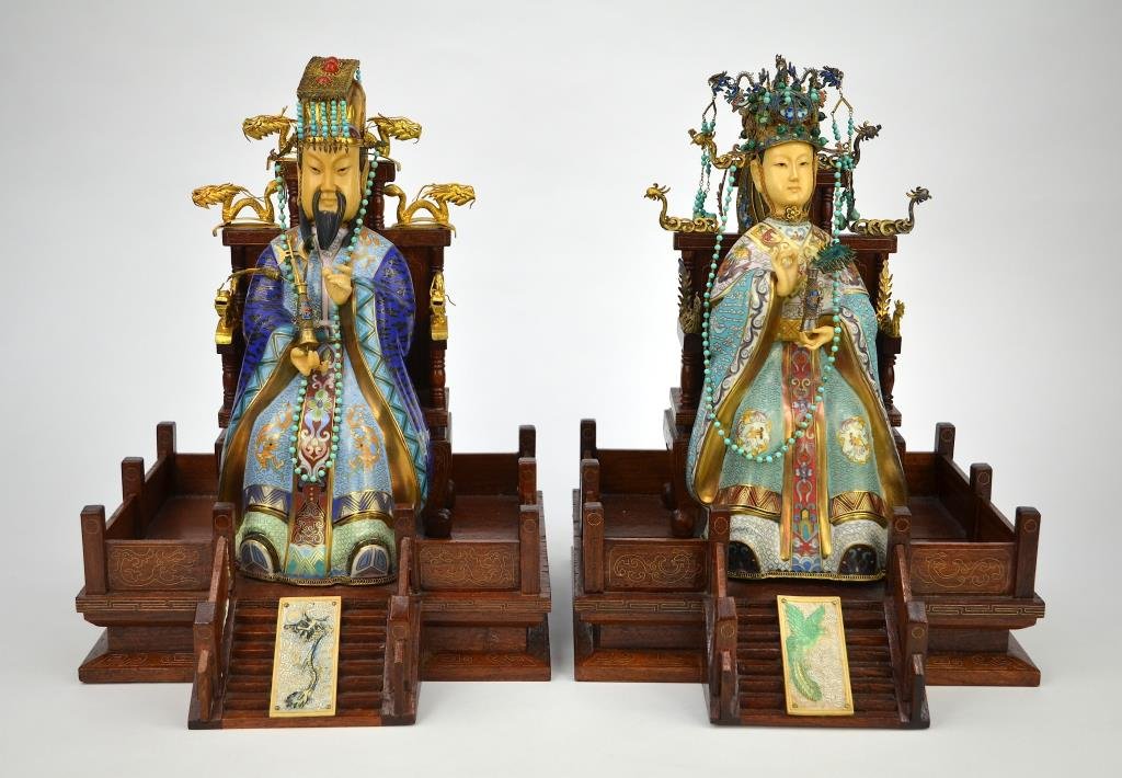 CLOISONNE AND IVORY FIGURES OF EMPEROR AND EMPRESS: Carved and painted ivory faces, seated on dragon and phoenix carved wood thrones, each holds a vase in hand. H. 38cm (15 in.) **INTERNATIONAL BUYERS: This item is restricted from export out of the cou