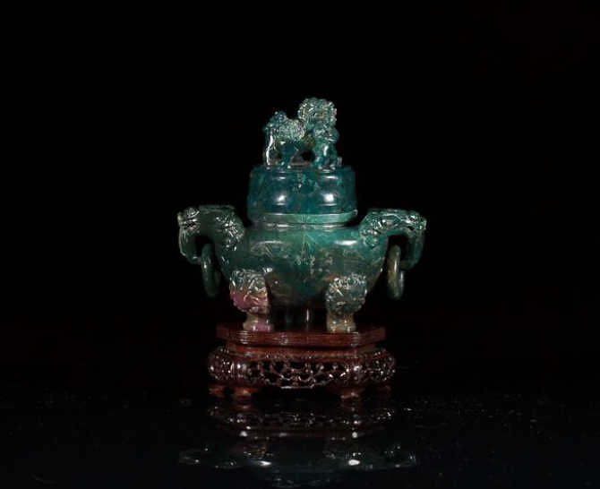 CARVED HARDSTONE TRIPOD CENSER: Double qilin-head handles with mobile rings, double fu-dog finial, censer of a green-blue stone with lavender inclusions. On carved fitted wood stand. W. 14.45cm (5 3/8 in.)