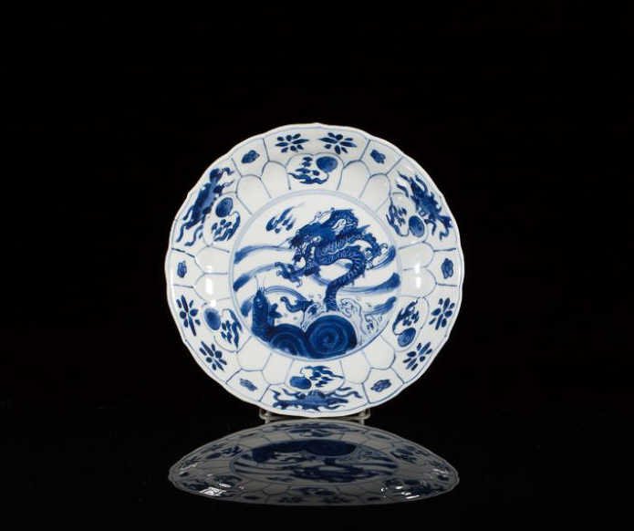 KANGXI BLUE AND WHITE PORCELAIN LOBBED DISH: Painted with a dragon and fish in waves. Six-character Ming Chenghua mark within double-circle. Dia. 15.5cm (6 1/8 in.)