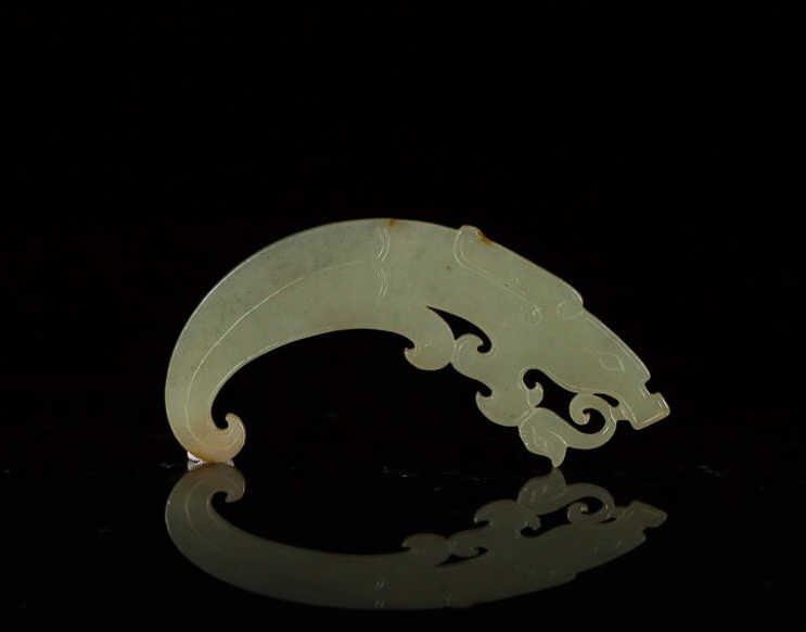GREEN JADE DRAGON ORNAMENTAL PLAQUE: Translucent dark celadon thin jade with a dragon head and curled tail, Western Zhou. L 8.3 cm. (3 1/4 in.) From the Irving Langleb collection, a prominent Jewish gentleman who resided in Japan post-WW