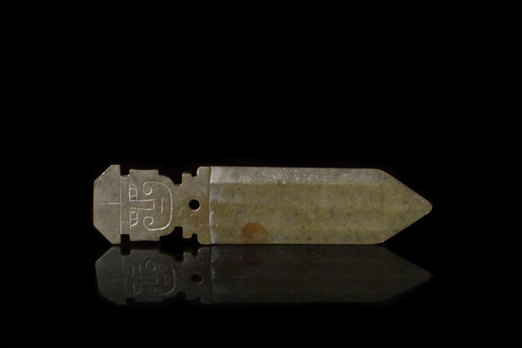 SPINACH GREEN JADE BLADE PENDANT: Carved on both sides of the pendant with a face morphing into a ribbed blade, possibly Shang Dynasty. L 8.5 cm. (3 3/8 in.) From the Irving Langleb collection, a prominent Jewish gentleman who resided