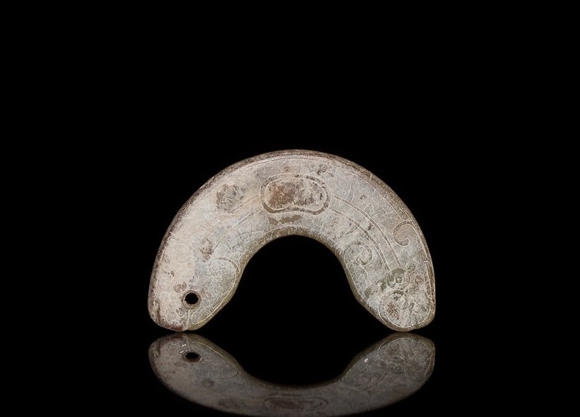 CALCIFIED GREEN JADE FISH PENDANT: Arched form with carved body of a head, late Shang to Western Zhou. W 8.6 cm. (3 3/8 in.) From the Irving Langleb collection, a prominent Jewish gentleman who resided in Japan post-WWII and was a clos