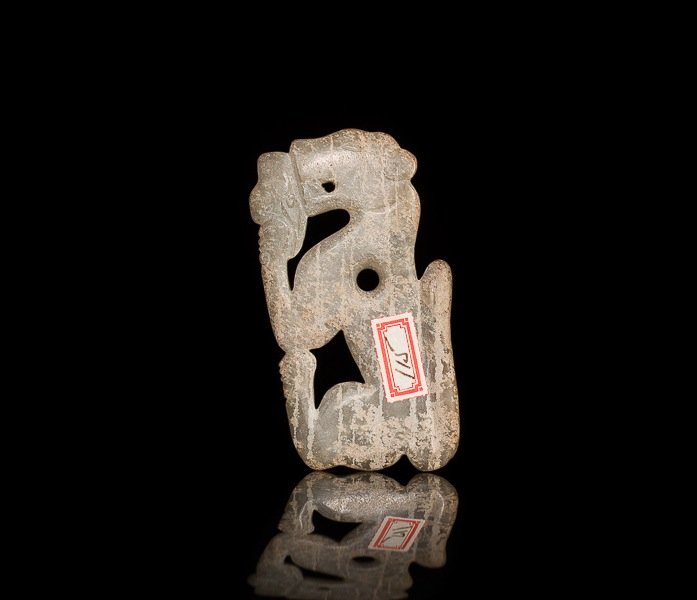 LIGHT CELADON GREEN JADE TIGER PENDANT: Carved on one side of a crouching tiger eating a phoenix head, surface calcifications, probably Shang. H 8 cm. (3 1/8 in.) From the Irving Langleb collection, a prominent Jewish gentleman who resided 