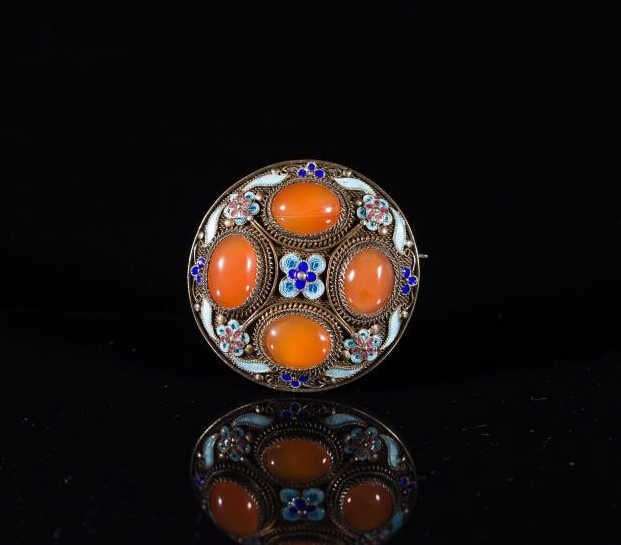 CHINESE ENAMEL AND CARNELIAN PIN: Silver filigree with carnelian cabochon inserts and enamel floral decorations. Back is stamped silver. Dia. 4.2cm (1 3/4 i.)