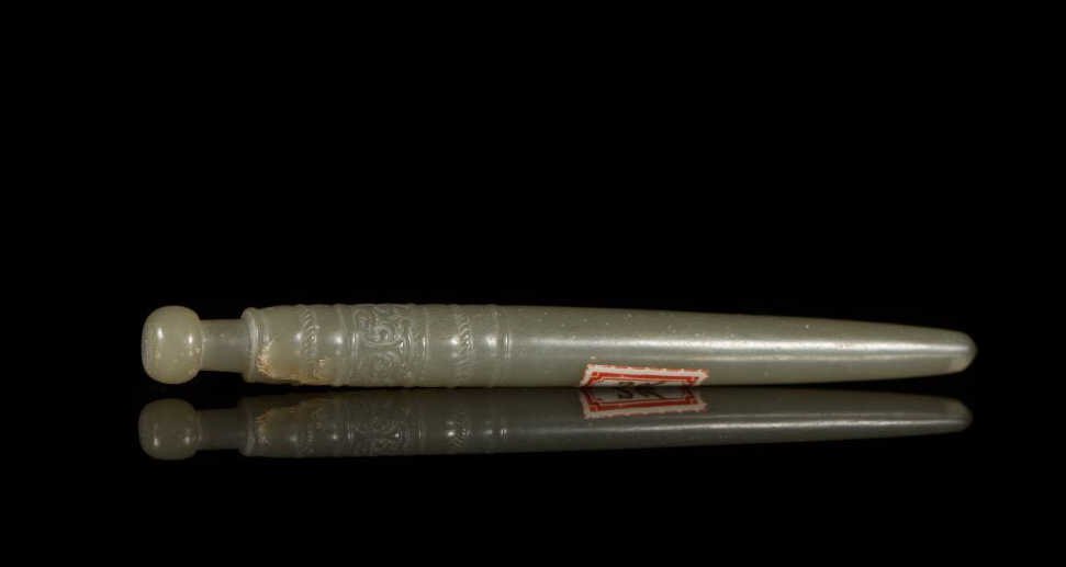 MING CELADON CARVED JADE HAIR PIN: Band of two taotie faces below a rounded knob. L 13.5 cm. (5 1/4 in.) From the Irving Langleb collection, a prominent Jewish gentleman who resided in Japan post-WWII and was a close friend to Prince M
