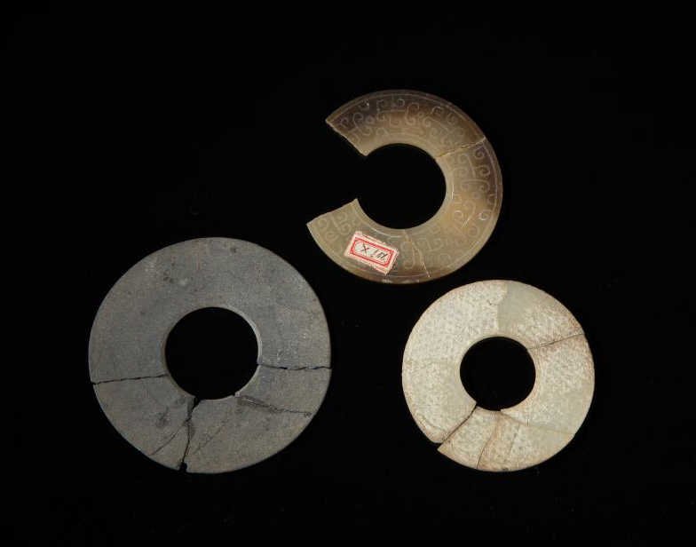 THREE EARLY JADE DISC FRAGMENT: In brown, calcified white and grey stone, Shang to Eastern Zhou. Dia of grey 10.2 cm. (4 in.) From the Irving Langleb collection, a prominent Jewish gentleman who resided in Japan post-WWII and was a 