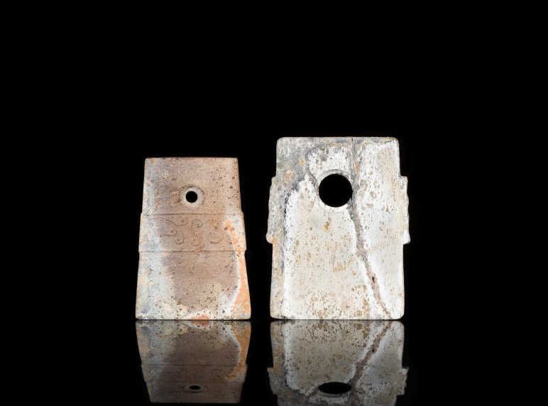 TWO NEOLITHIC JADE HOE PENDANTS: Mixed stone colouration, biconical hole in each, smaller example with a band of relief decoration. Both for ceremonial purposes. H 6.5 cm. (2 1/2 in.) From the Irving Langleb collection, a prominent J