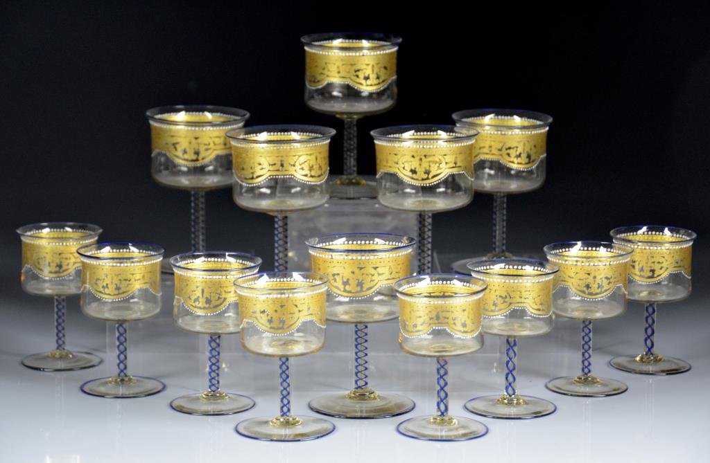 FOURTEEN FINE ITALIAN MURANO GLASS STEMS: Attributed to Salviati, gold stenciled design lined in white enamel beading. Blue air twist stems and blue rims, early 20th C. Including six small wines and eight liquor glasses. H of wine 11 cm. (4 1