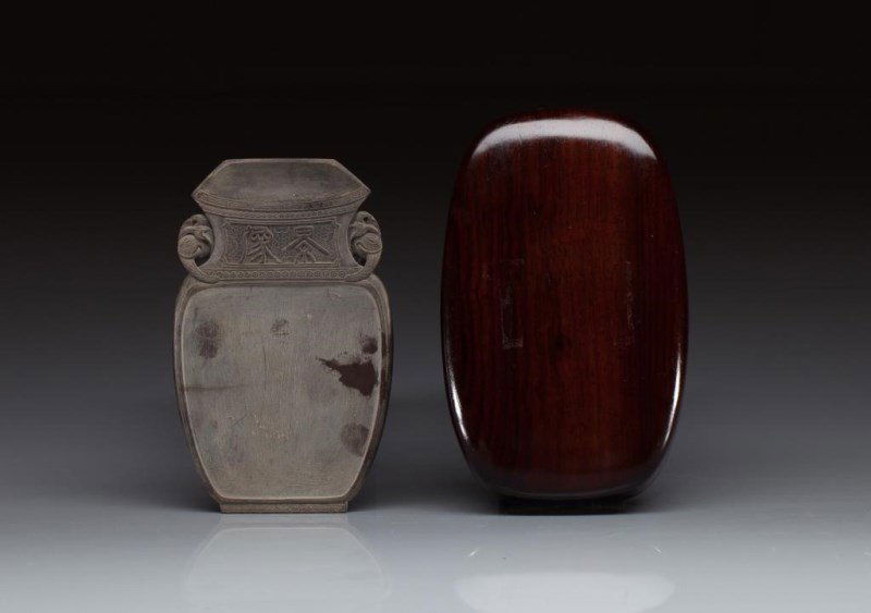 VASE FORM INKSTONE & HARDWOOD BOX: Carved with decorative floral scrolls and two elephant heads as handles. Inscribed with "Jing Xiang" (auspicious times) characters on a webbed ground. With fitted hardwood box. 18th to 19th C. Size: 1