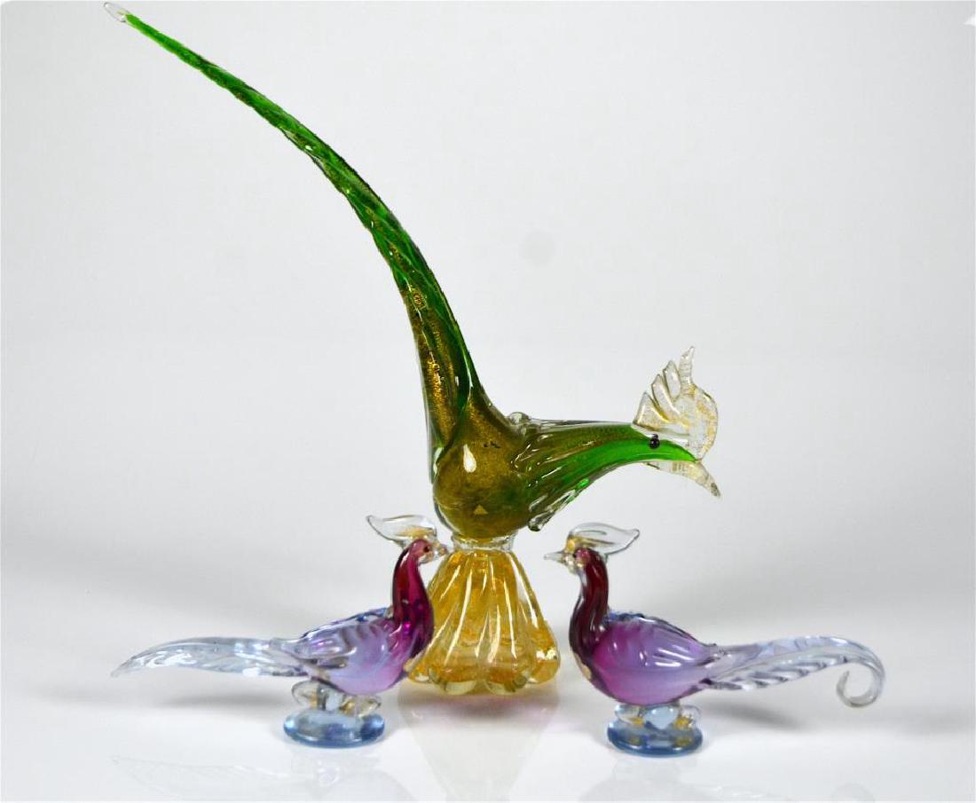 THREE MURANO GLASS BIRDS: Including a pair of purple Venetian pheasants by Alfredo Barbini, and a larger green pheasant with gold inclusions retailed by Birks. H of green bird 36.8 cm. (14.5 in.)