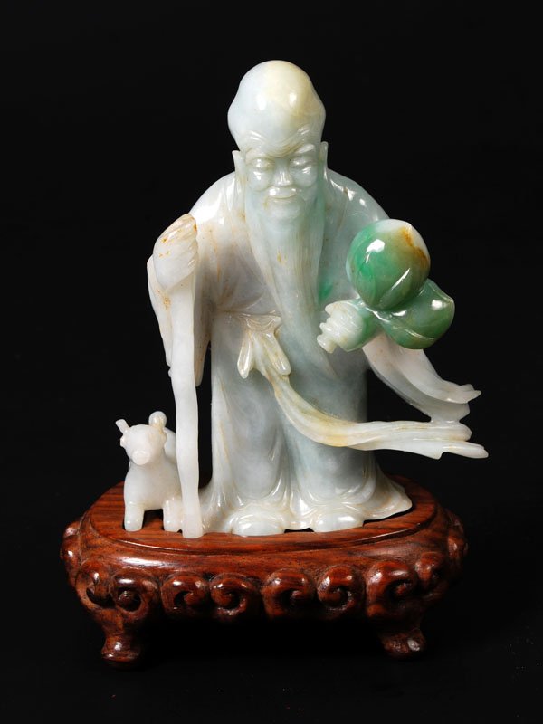 A Chinese pale green jadeite figure of ShouLao,sta: A Chinese pale green jadeite figure of ShouLao,standing in flowing robes holding a peach branchand a staff supporting a gourd, 12cm
