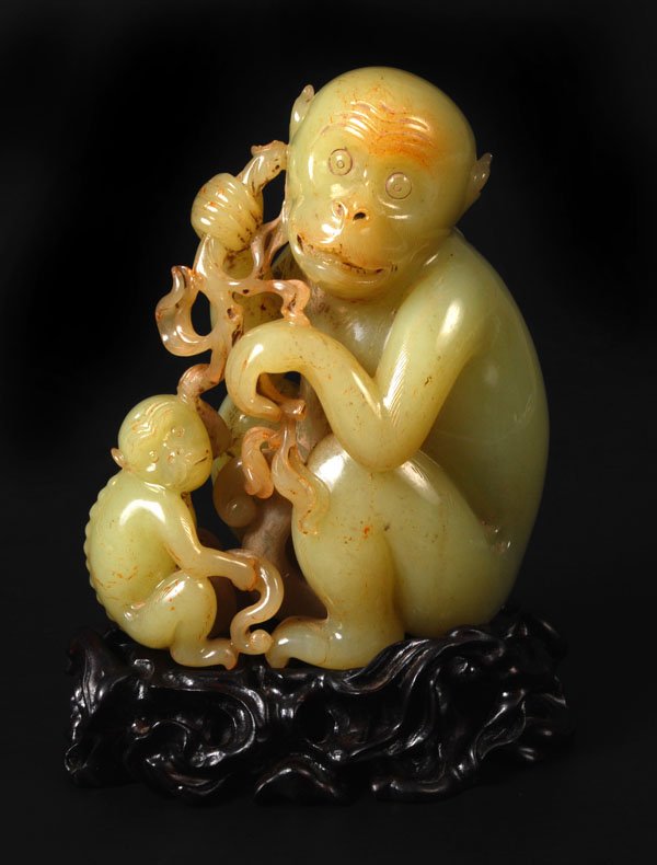 A Chinese celadon jade group of a monkey andbaby,: A Chinese celadon jade group of a monkey andbaby, each grasping a leafy branch, the stonewith slight russet inclusions, 12.5cm high