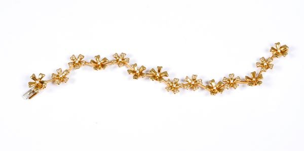A diamond bracelet by De Beers, composed of 14 flo: A diamond bracelet by De Beers, composed of 14 flower head clusters set with brilliant-cut diamonds, mounted in 18 carat yellow gol