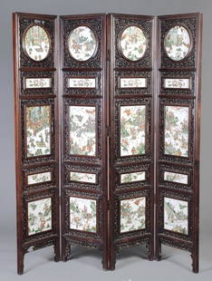 A Chinese four-fold huanghuali and porcelain mount: A Chinese four-fold huanghuali and porcelain mounted screen, late 19th/early 20th century, the circular and rectangular panels decorated in famille verte with scenes of dignitaries a qilin an