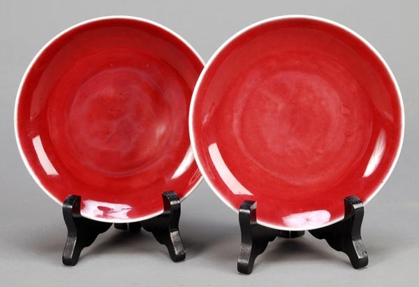 A pair of Chinese sang-de-boeuf glazed saucer dish: A pair of Chinese sang-de-boeuf glazed saucer dishes, 18th century, 15.3cm diameter, wood stands