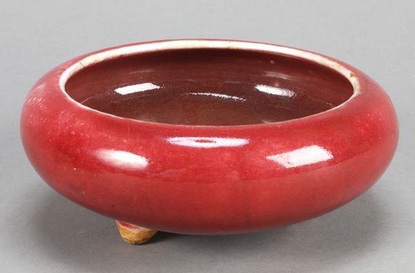 A Chinese sang-de-boeuf censer, 18th century, of s: A Chinese sang-de-boeuf censer, 18th century, of squat form, on three stump feet, 14cm diameter