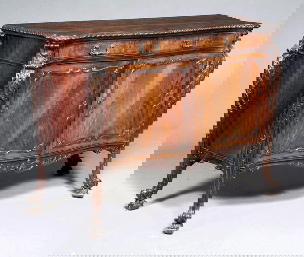 A mahogany commode in George III style, after a de: A mahogany commode in George III style, after a design by Thomas Chippendale, late 19th / early 20th century, top with gadrooned edge, two drawers, pair of cupboard doors flanked by acanthus