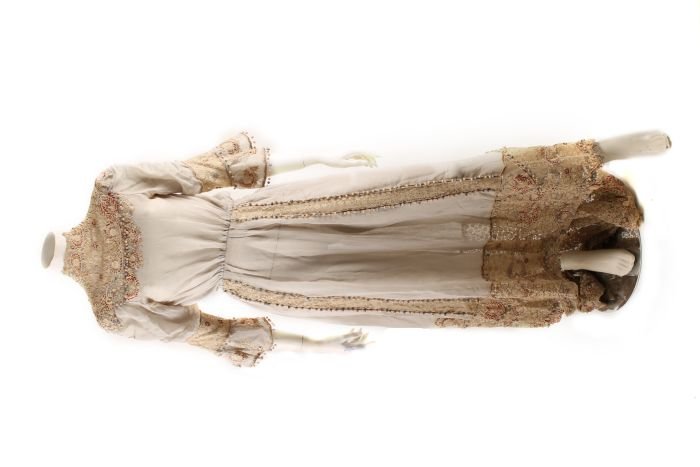 An Edwardian grey dress, with cream lace and red d: An Edwardian grey dress, with cream lace and red decoration; together with a green silk skirt; calico pantaloons and smock with red embroidered initials 'ABM' and the name 'Amy'; a short blac