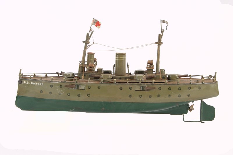 A Marklin tinplate battleship, circa 1910, grey-gr: A Marklin tinplate battleship, circa 1910, grey-green with brown decks, equipped with two masts, two funnels and six rotating twin-barrelled guns, the superstructure removable, the bow later
