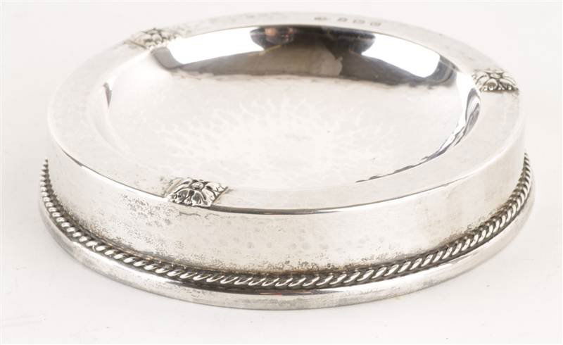 An A.E. Jones silver pin tray, Birmingham 1927, of: An A.E. Jones silver pin tray, Birmingham 1927, of circular dished form, with three foliate motif at points, cord border, loaded, 10.5cm diameter