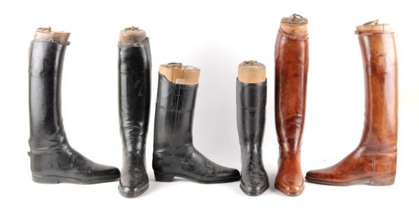 Two pairs of black leather riding boots, the wood