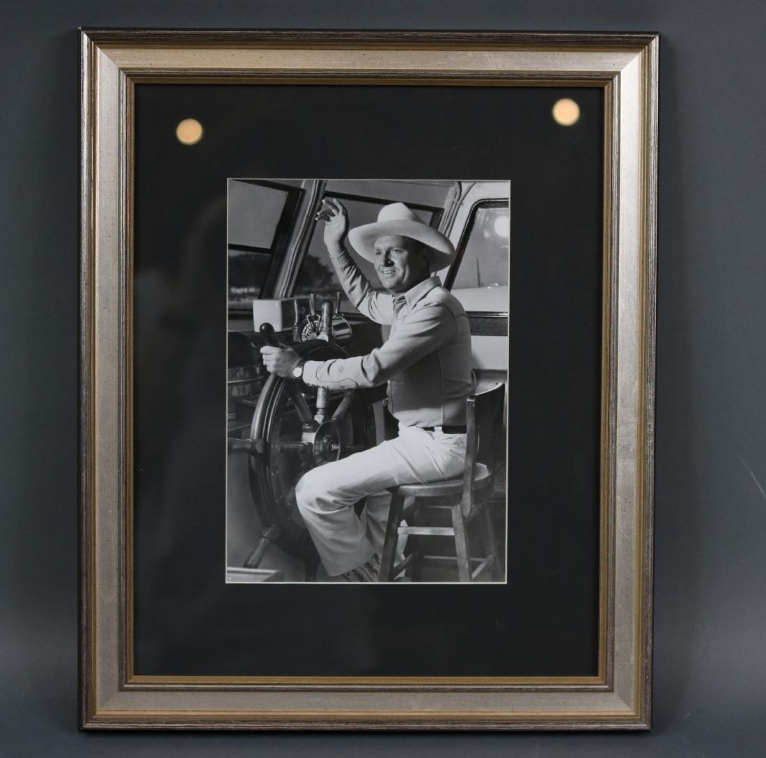 Photo of Gene Autry on a Yacht: Original black and white photograph showing country legend Gene Autry at the helm of a large motor yacht . Autry is surrounded by a shipâ€™s wheel, binnacle, compass, bridge telegraph etc.. Matte