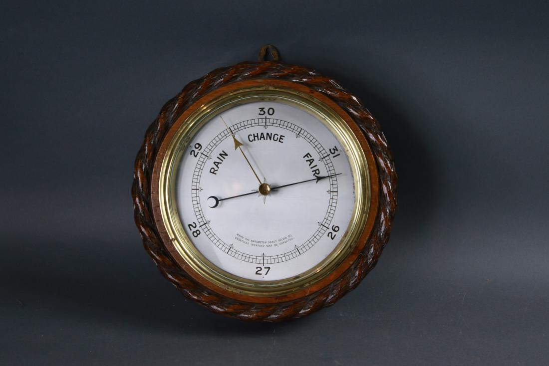 Edwardian library barometer: Edwardian barometer in oak case with carved rope border and solid brass bezel, glass face and engraved faceplate. Adjustment screw to rear. Overall diameter is 12 inches.
