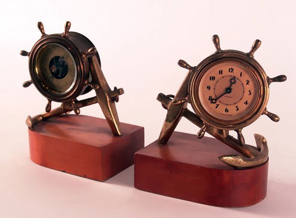 Ship clock and barometer bookends.: Brass ship's clock and barometer set. Clock is by Plymouth, Made in the USA. With ship's wheel cases attached to anchors, mounted on wood bases. Key wound mechanism in clock. Bellows style barometer i