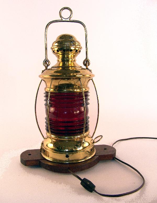 Early 20th century Perko distress lantern: Early Perko lantern made of solid brass with original badge, bale handle, deep ruby red lens and protective brass bars. Set onto a wood base with a/c socket and cord. 8" diameter x 15" high without ha