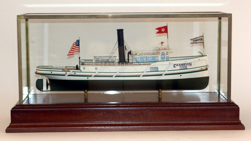 Scale model of Great Lakes tug "Champion".: Well executed model of the Great Lakes tugboat "Champion", with white hull, detailed cabins, planked deck, fittings, flags, etc... Mounted into a fine marquetry inlaid display case. 23" x 9" x 11"