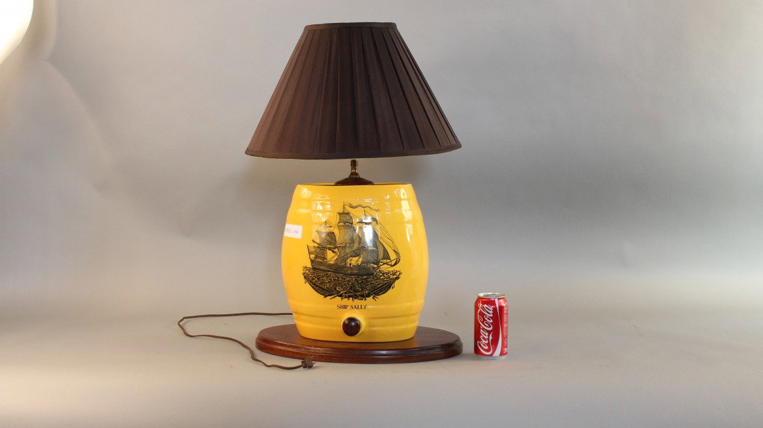 Ceramic "Keg" Lamp: Lamp with keg style base of ceramic showing a tall ship on water in center titled "Ship Sally". Keg is yellow with faux wood spout and blue silk shade. Keg is mounted to an oval wood base. 27" high x 