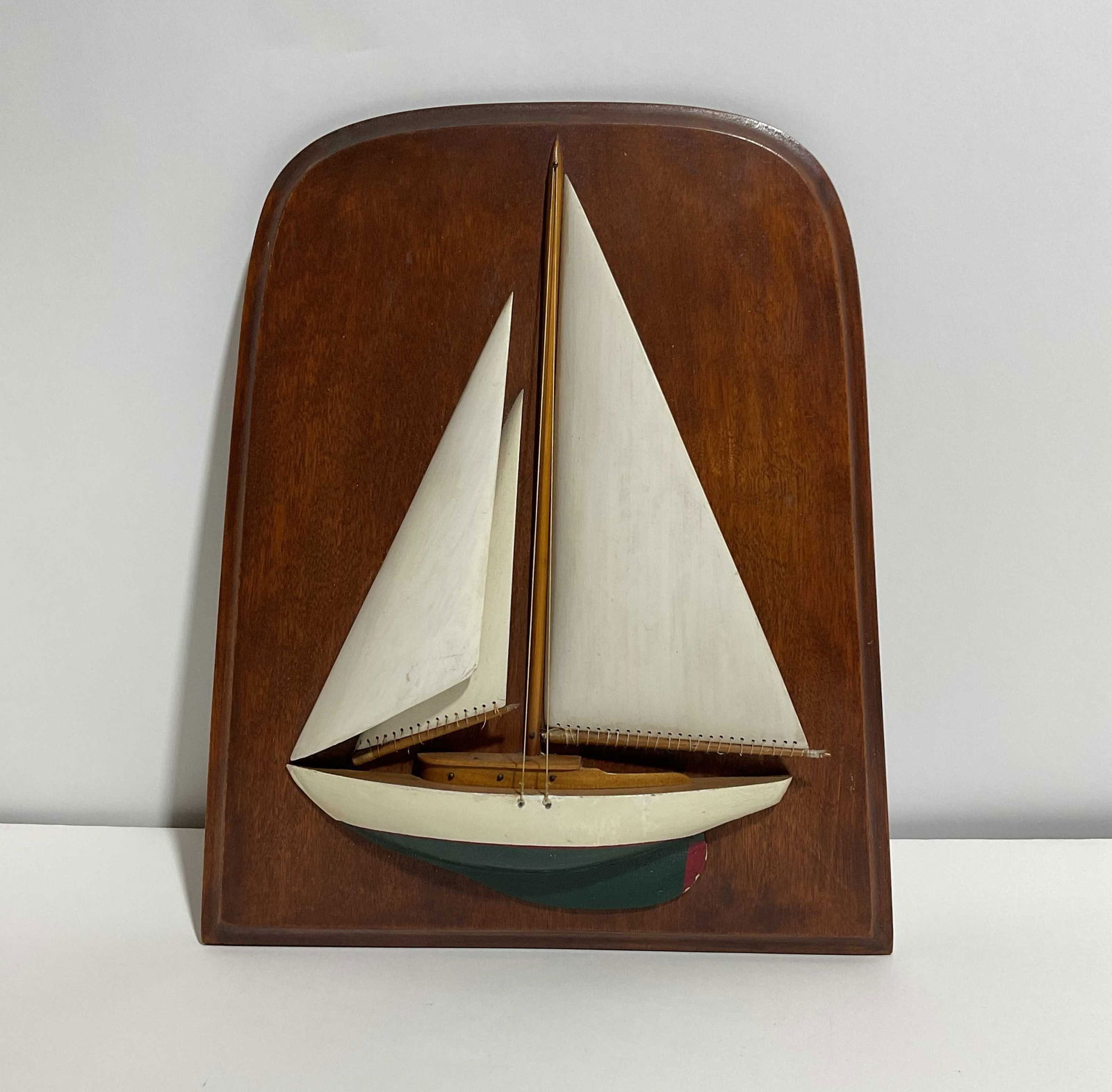 Half Model of a Sailing Sloop on Board: Antique half model of a yacht with wood sails, cabin, painted hull, mounted to a backboard. Hull is painted white over green, great nautical accent piece. 12x10 H-L 2 lbs.