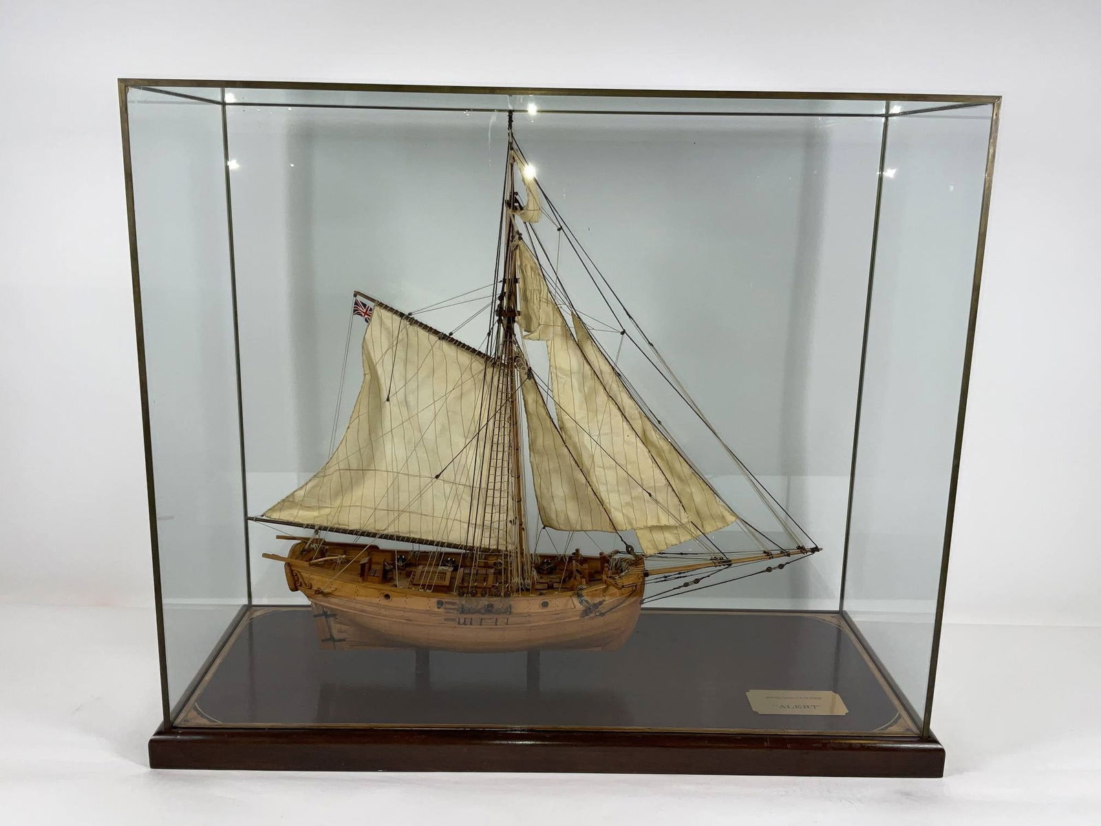 English Cutter Ship Model in Case: Plank on frame ship model of the English cutter "Alert". The planked deck carries eight guns, hatches, bells, pump, capstan, tiller, etc.. The pinrails are filled with rigging cords. Rigged with a ful