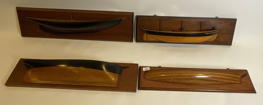 Four Carved Ship Half Models as a Lot: Group of four boat half models including a fishing schooner, a bark, brig and launch. All are mounted on backboards. Largest backboard. Smallest backboard. 8" H x 28" W.