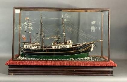 Folk Art Ship Model of a Steamship: Charming model of a coastal steamship set into clay waves and a felt lined glass and wood display case. Intricate model with exceptional cabin detail with arch top windows, skylights, carved wood figu