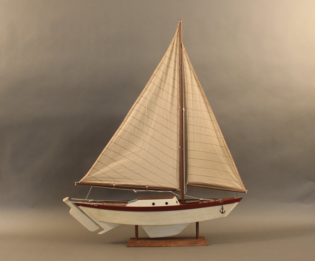 Model of a sloop: Wooden model of a sloop with raised cabin and stiched sails displayed on a cradle. 27” x 8” x 34
