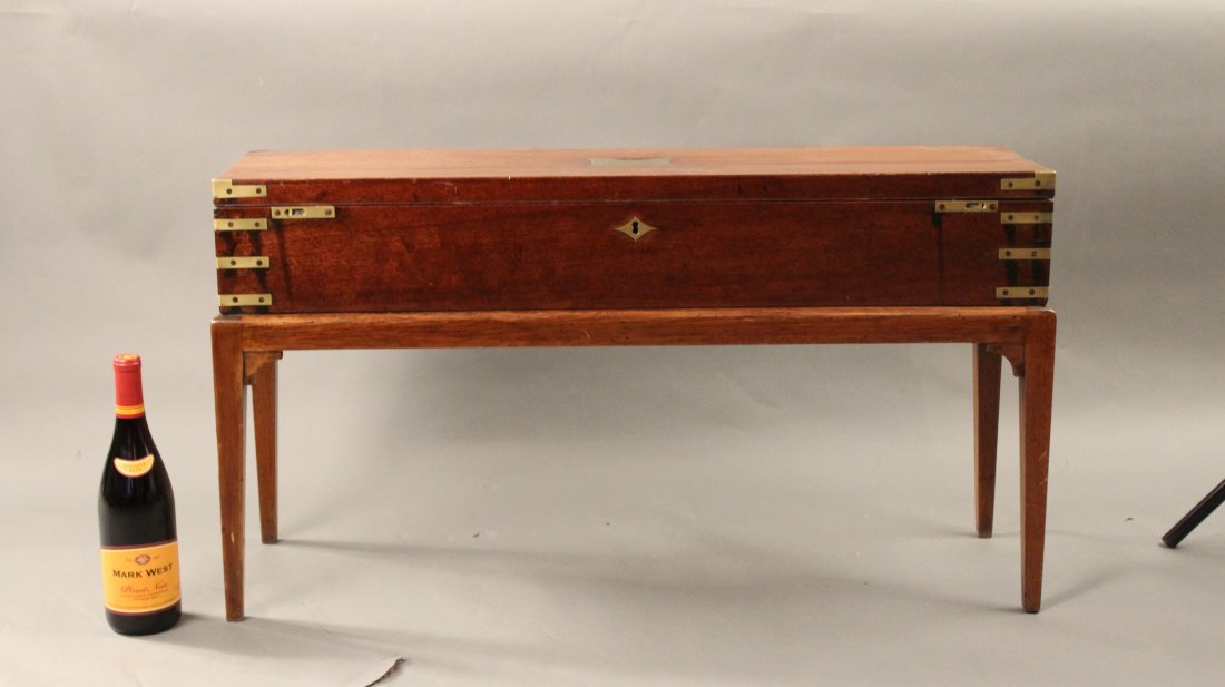 Mahogany and brass campaign chest: 19th century brass bound campaign chest fitted to a table stand. Chest has a lift out tray, inlaid keyhole and top pull handle. 34 1/4” long x 9 1/4” wide x 5 1/2” tall. Overall dimensions inclu