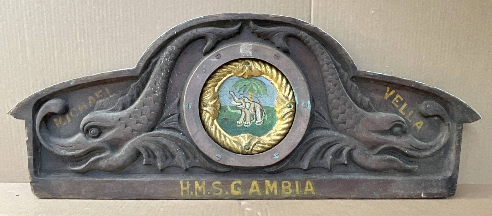 Royal Navy Captain's Gig Seatback from HMS Gambia 1940: Carved seat back from the captain's gig onboard HMS Gambia, with wonderful carving work that includes mythical dolphins and the ship's badge. Gambia steamed 503,000 miles in her twenty-year Navy caree