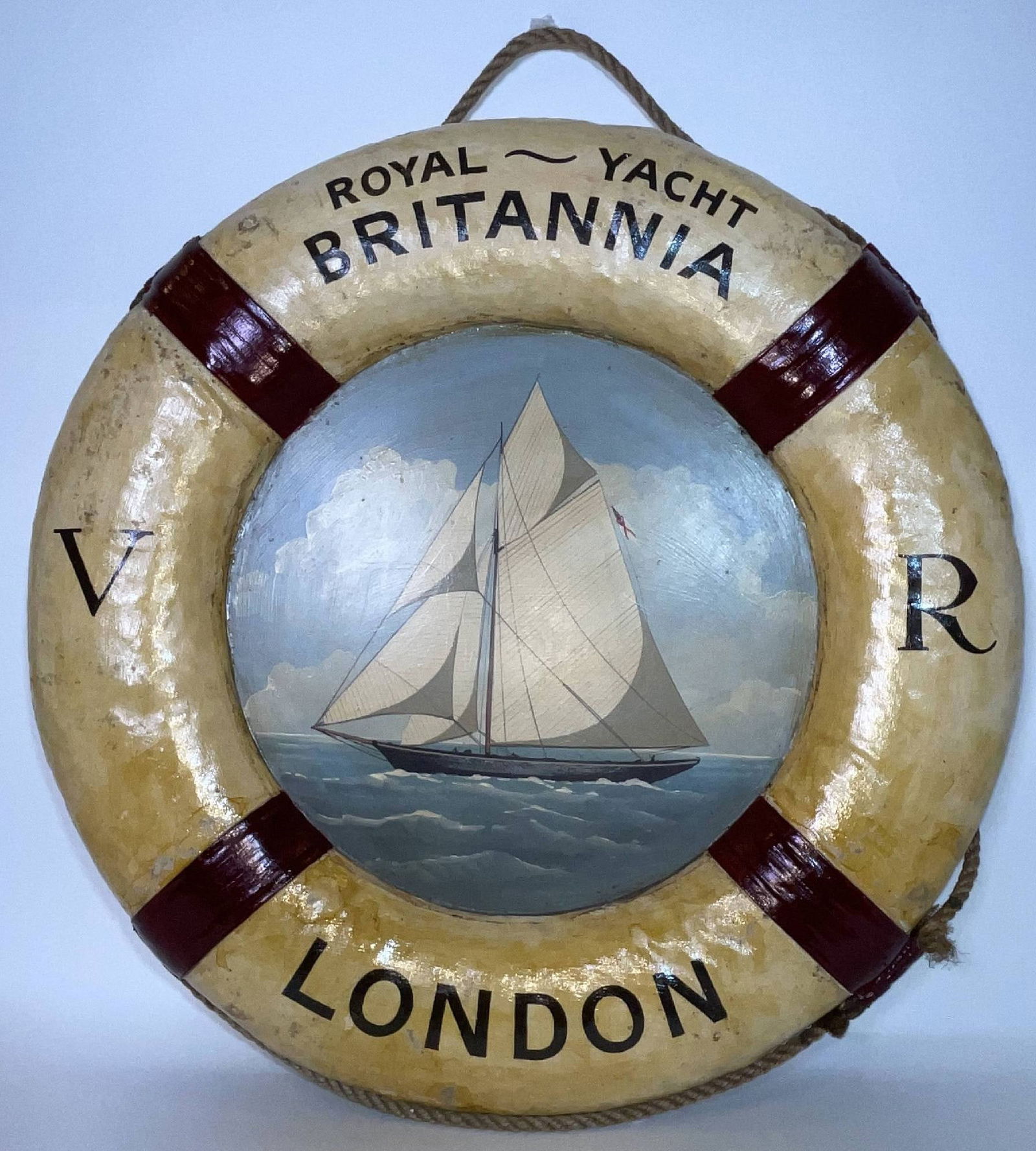 Royal Yacht Britannia Lifering with Painted Portrait on Panel: Canvas covered life ring with rope and straps. With painted decoration on a wood panel showing the Royal Yacht Britannia under full sail. This is later artwork. 13 lbs. 30" Diameter.
