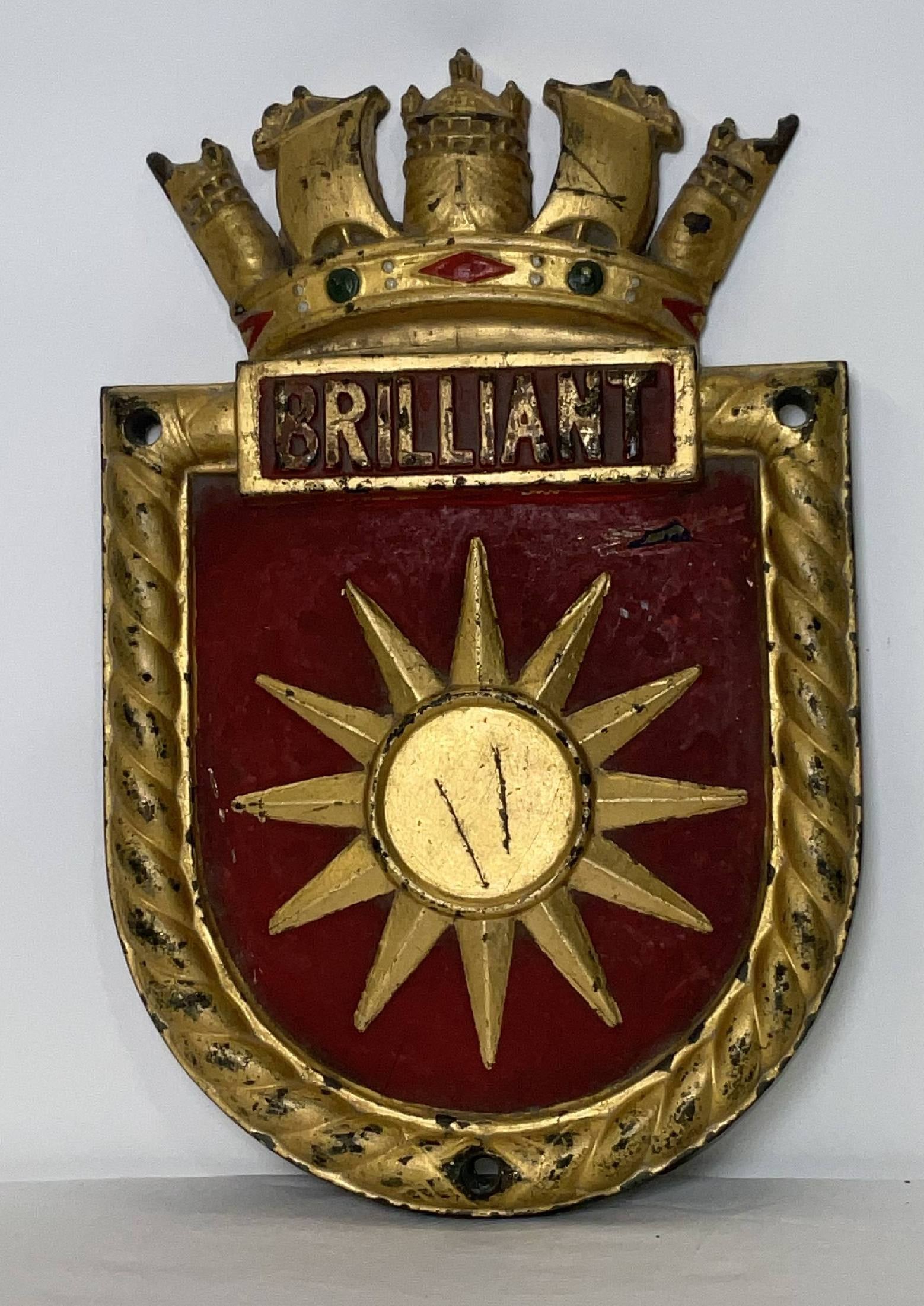 Gilded Screen Badge for HMS Brilliant of the Royal Navy: Bronze screen badge from HMS Brilliant, a B-class destroyer that served the Thames River and Thames Estuary. The ship's badge is a twelve-pointed star. Gilded finish with a red field. 17 lbs. 15"H x