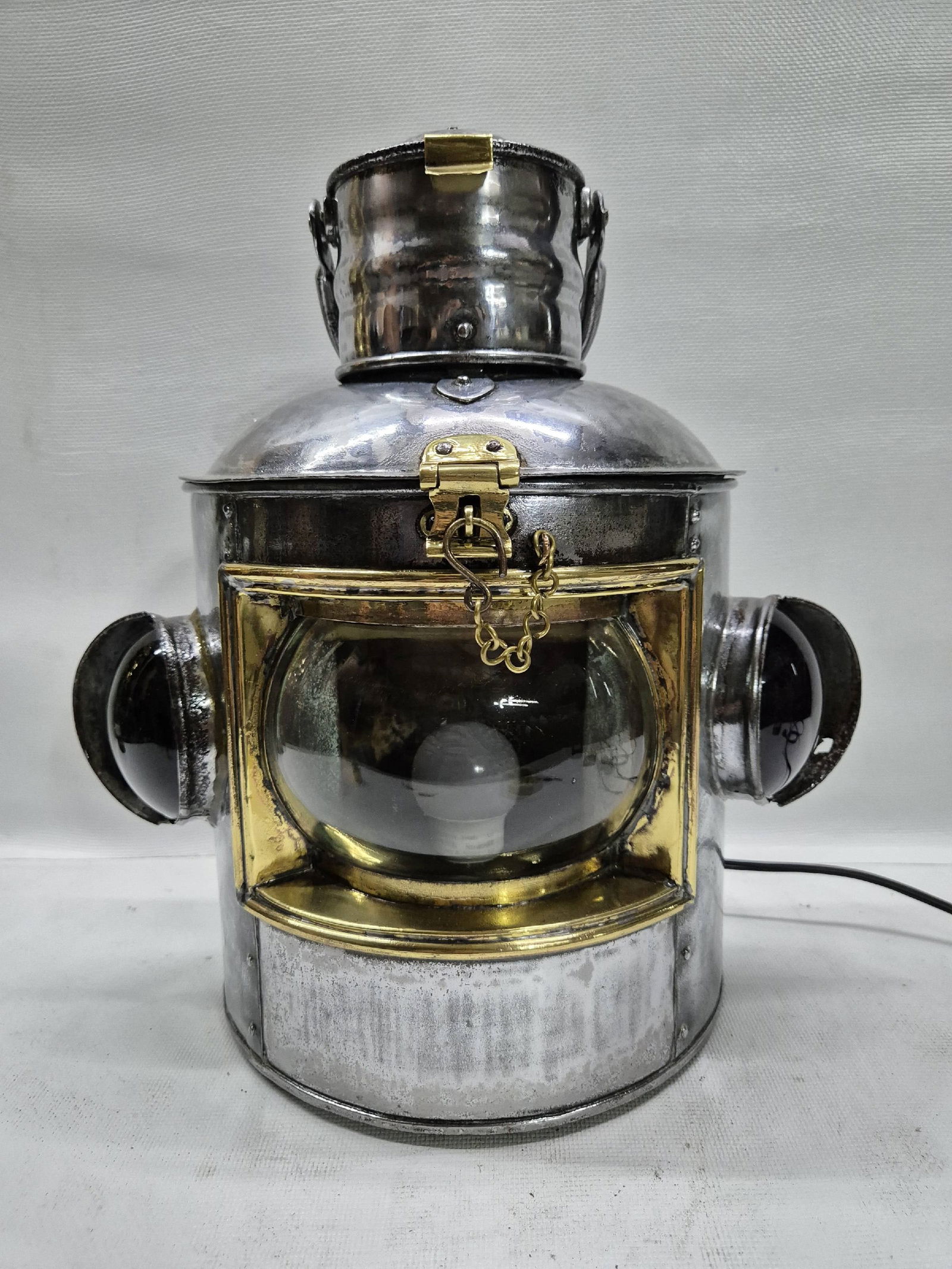 Polished Triple Lens Marine Lantern That is Very Large: Antique ship's lantern with clear curved masthead, port and starboard bullseye lenses. Hinged and vented top, brass hasp, carry handle. Great design. Wire with electric socket. The photo doesn't show