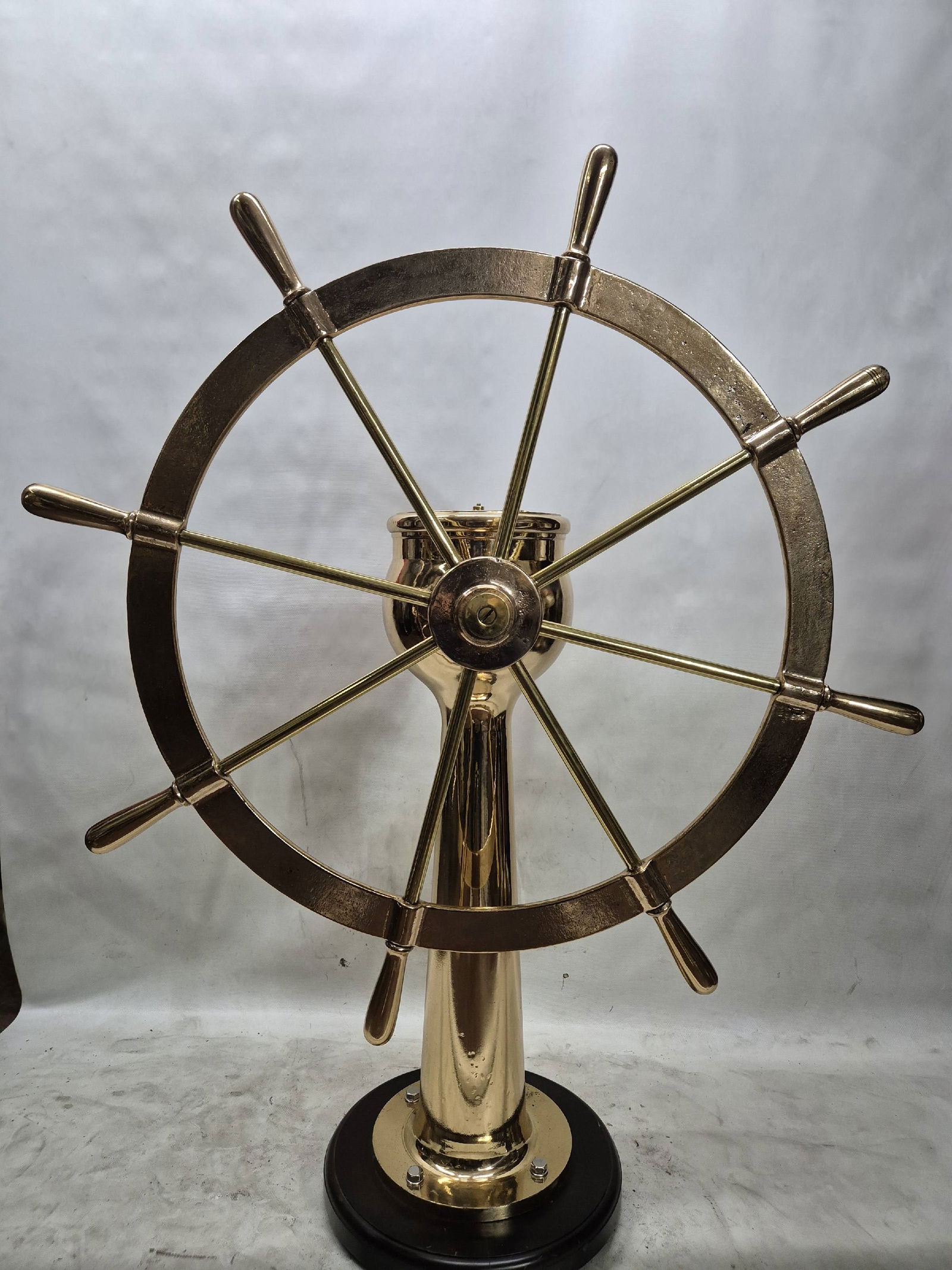Solid Brass Ships Wheel on Pedestal: Stunning and heavy ships wheel mounted to a brass pedestal. Fitted with a rudder indication arrow. Meticulously polished and lacquered. Mounted to a wood base.