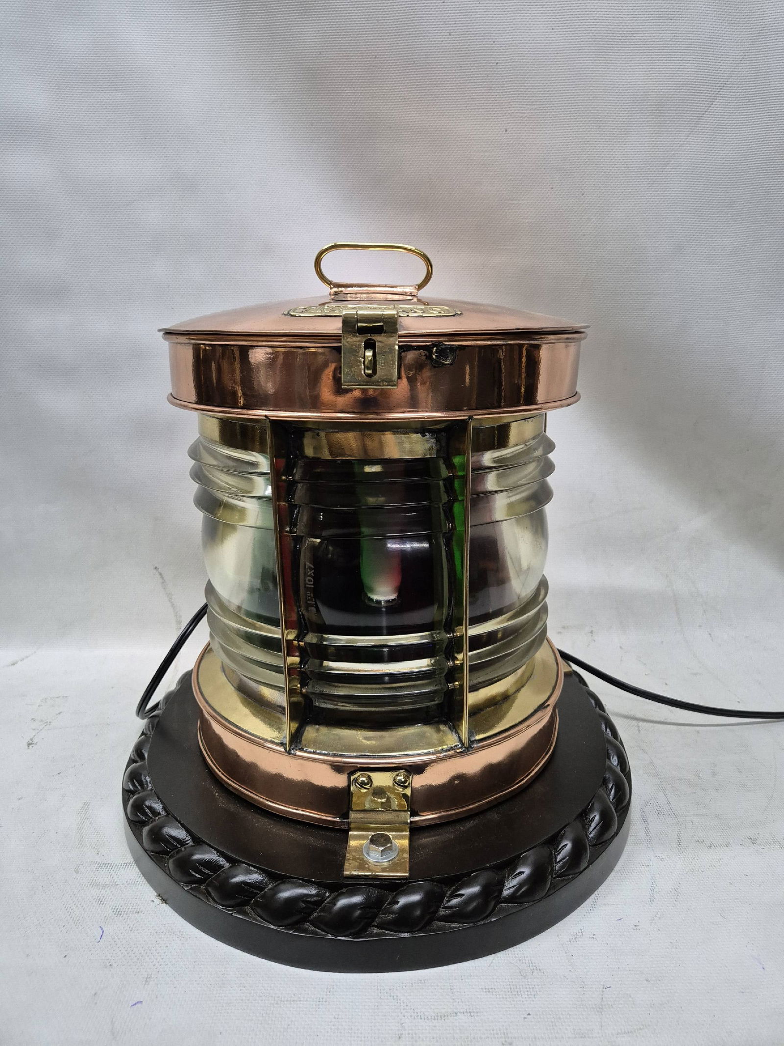 Solid Copper Ships Bow Lantern with Colored Lenses: Highly polished and lacquered ships lantern with clear Fresnel lens and red and green filters. Wired for home use. Mounted to a thick wood base with rope carved border
