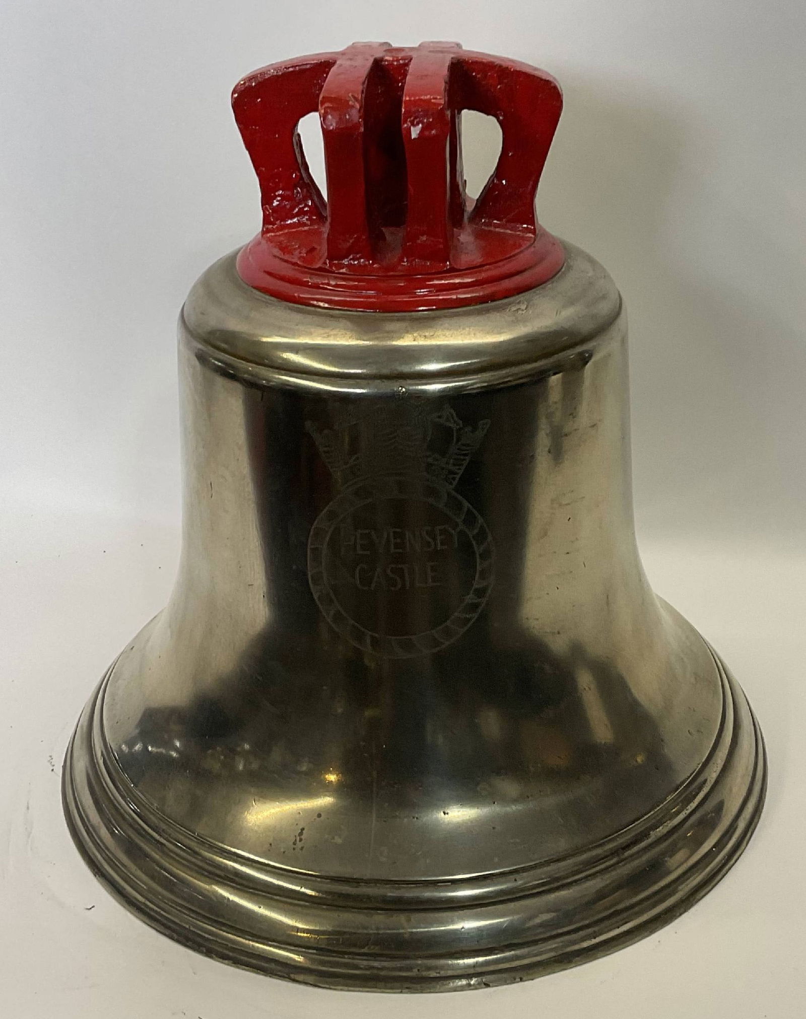 Bell from H.M.S. Pevensey Castle: Solid brass bell from the ship H.M.S. Pevensey Castle, engraved with the ship’s name within a naval crest. H.M.S. Pevensey Castle was a Castle-class corvette of the British Royal Navy, built during