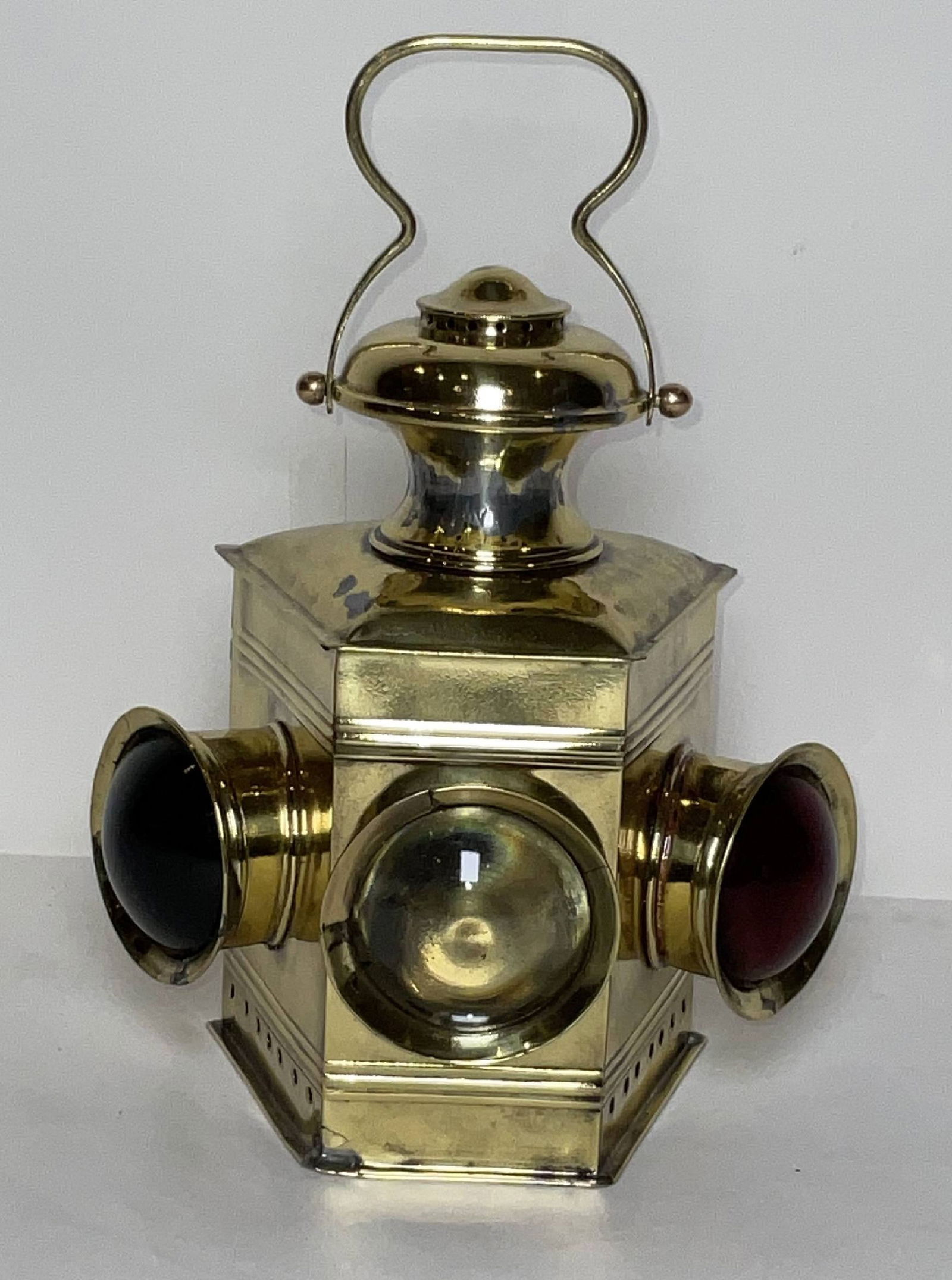 Tri Lens Boat Lantern with Bullseye Lenses: Polished brass boat lantern with three bullseye lenses. There is a clear, red, and blue lens. Fitted with an oil burner, vented top, carry handle, hinged door, etc. 4 lbs. 8"H x 7"W x 5"D.