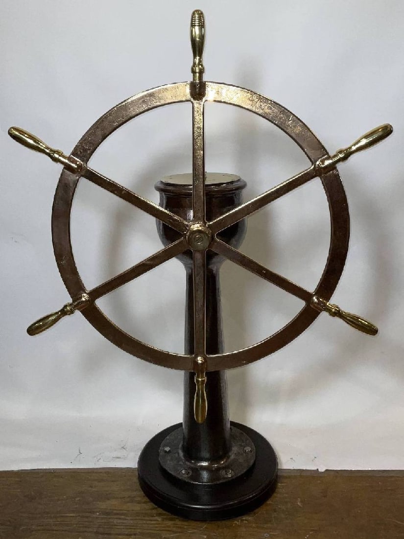 Ship's Wheel on Stand by Wheeler of C.H. Wheeler Manufacturing Company of Philadelphia: Ships wheel on iron pedestal with brass plate that has rudder indicator arrow pointing left and right. Fitted with a solid brass six-spoke ship's wheel that has been polished and lacquered. Mounted to