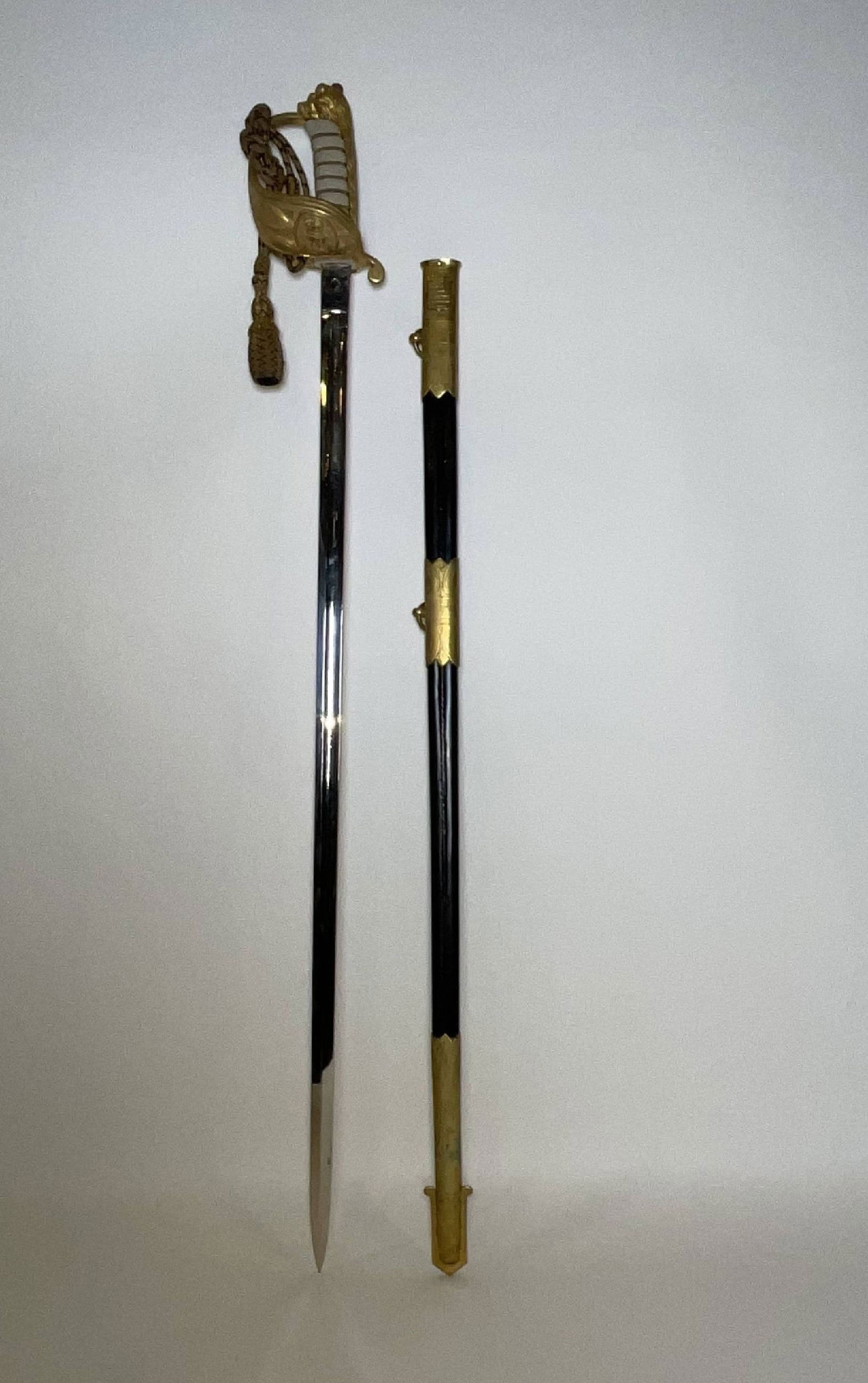 British Royal Navy Ship's Officers Sword with Sheath: Royal Navy sword with maker’s badge from S.W. Silver & Company, outfitter, Portsmouth and London. Handle has Royal crown and fouled anchor. Attached rope with tassel. 2lbs. 37"long